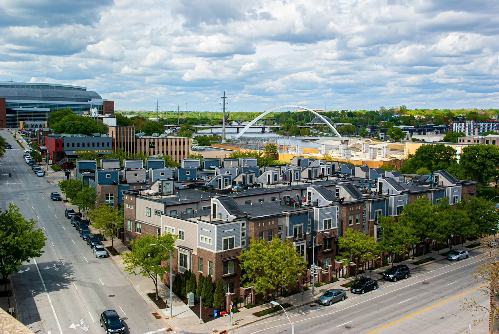 Aerial view of modern townhouses and residential buildings in an urban neighborhood with bridge in background