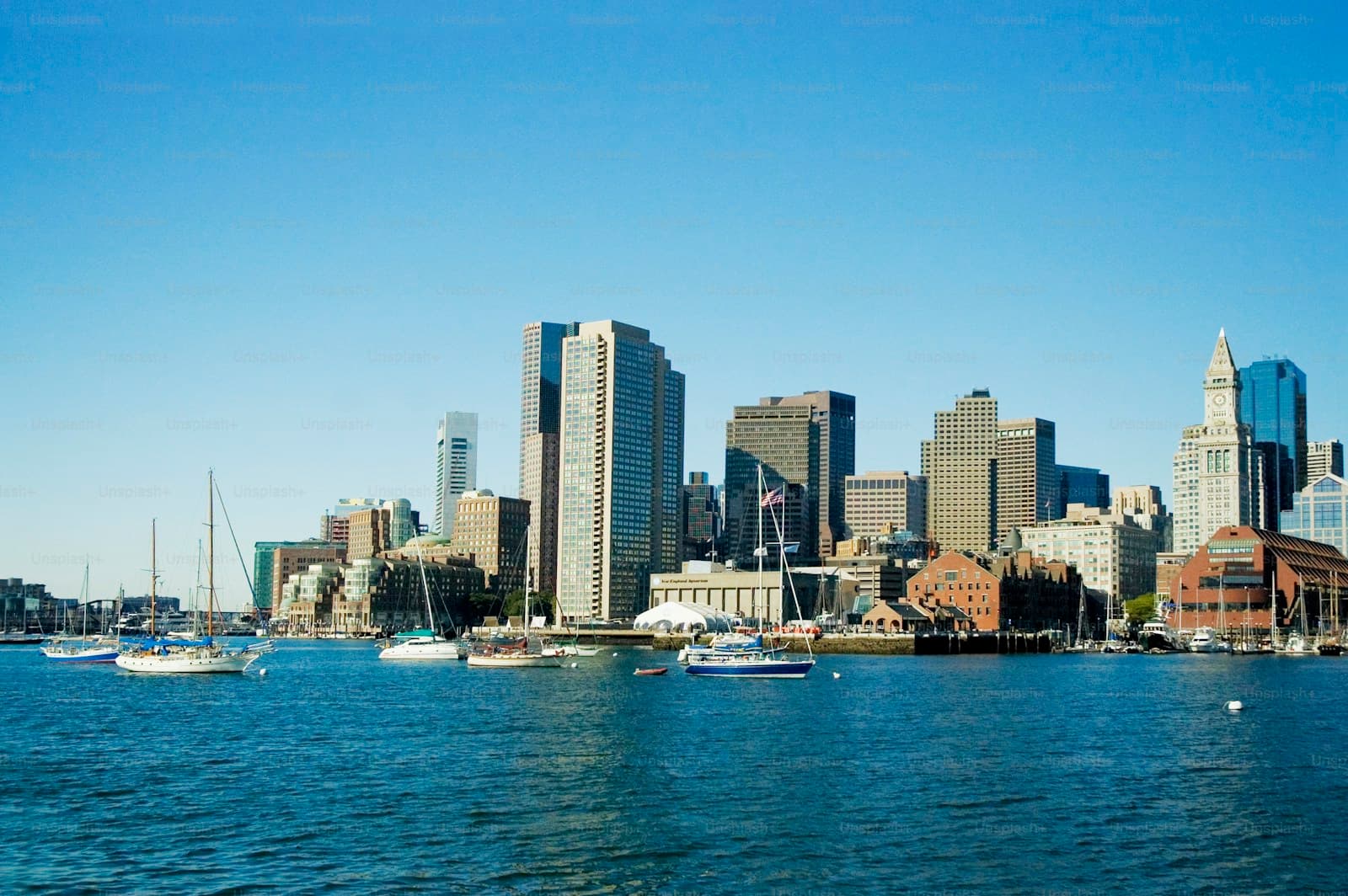 Boston skyline view from the harbor with sailboats in foreground and downtown buildings on clear day