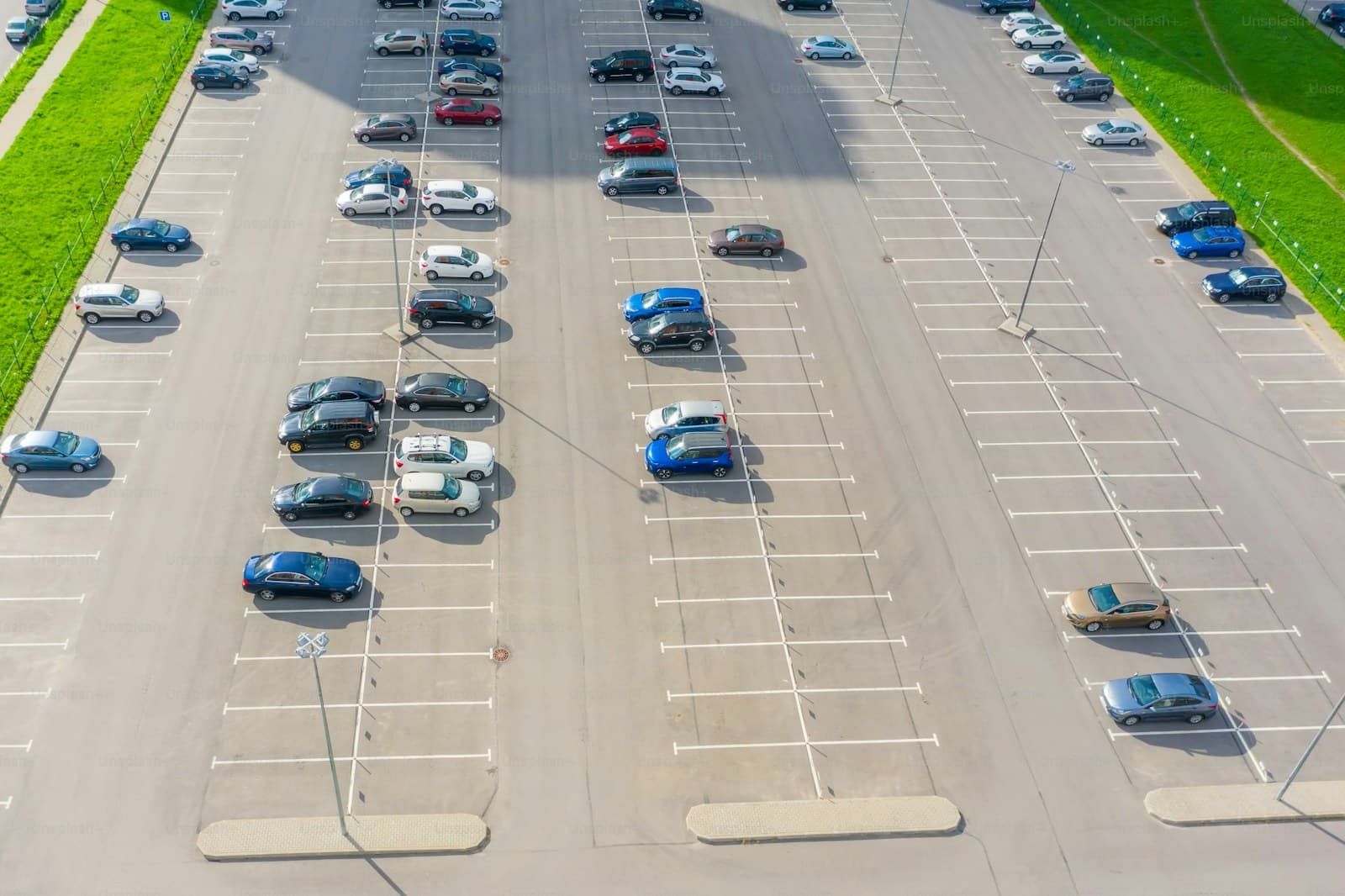 Aerial view of parking lot with cars in marked spaces and grass borders