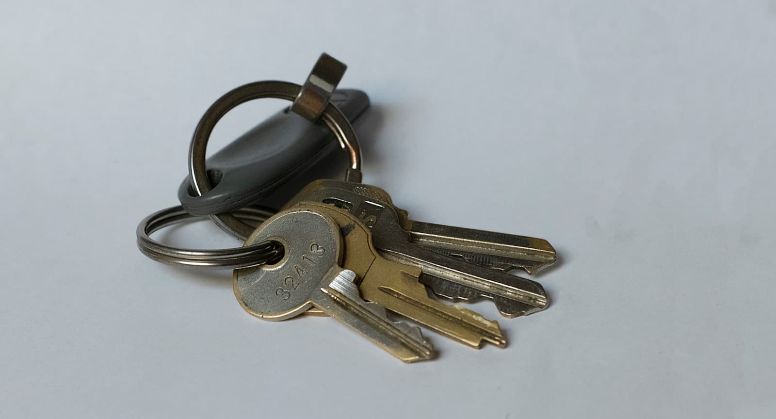 Brass keys on a ring resting on a plain light-gray surface
