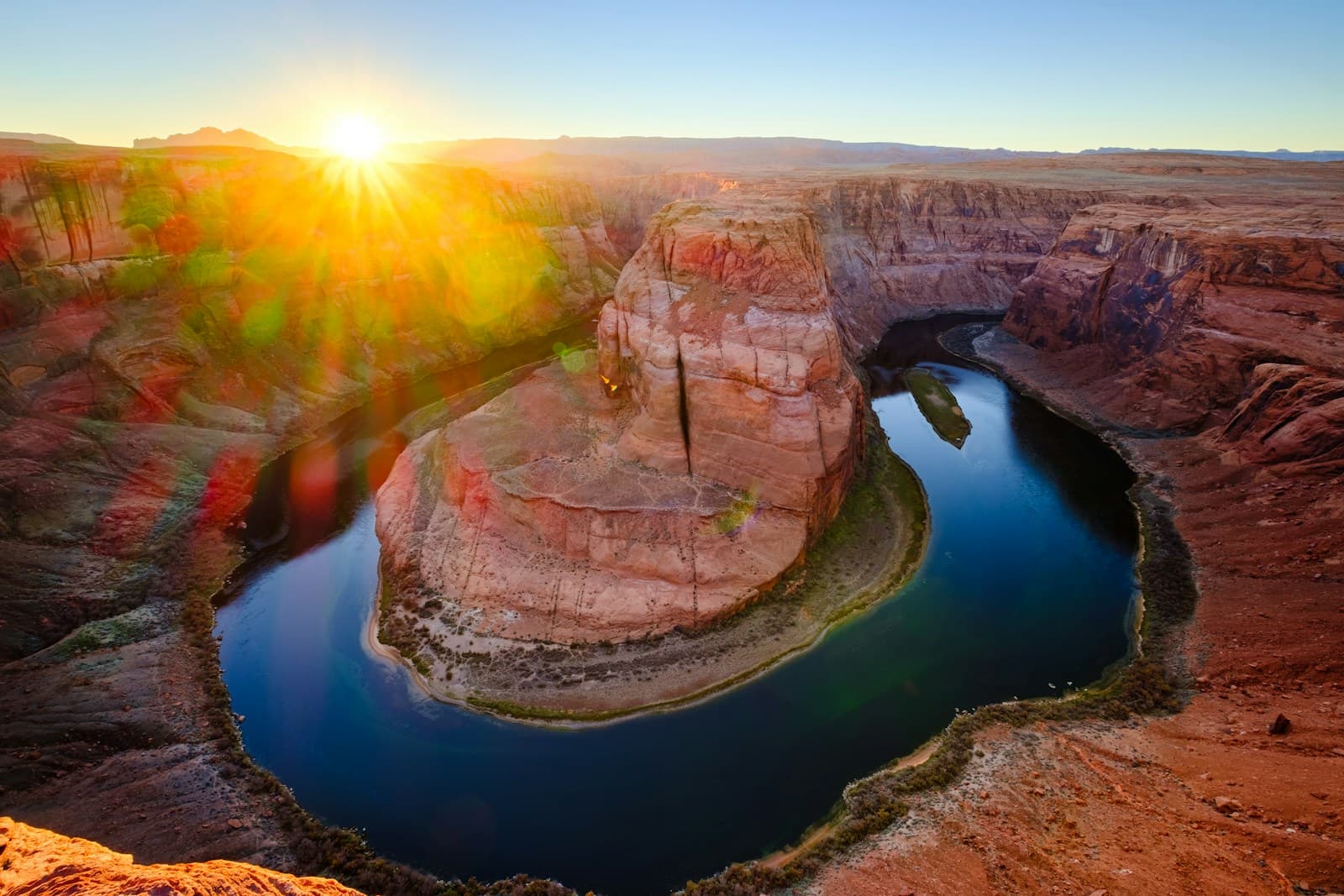 Horseshoe Bend at sunset showing Colorado River's curved path through red canyon walls with golden sunlight