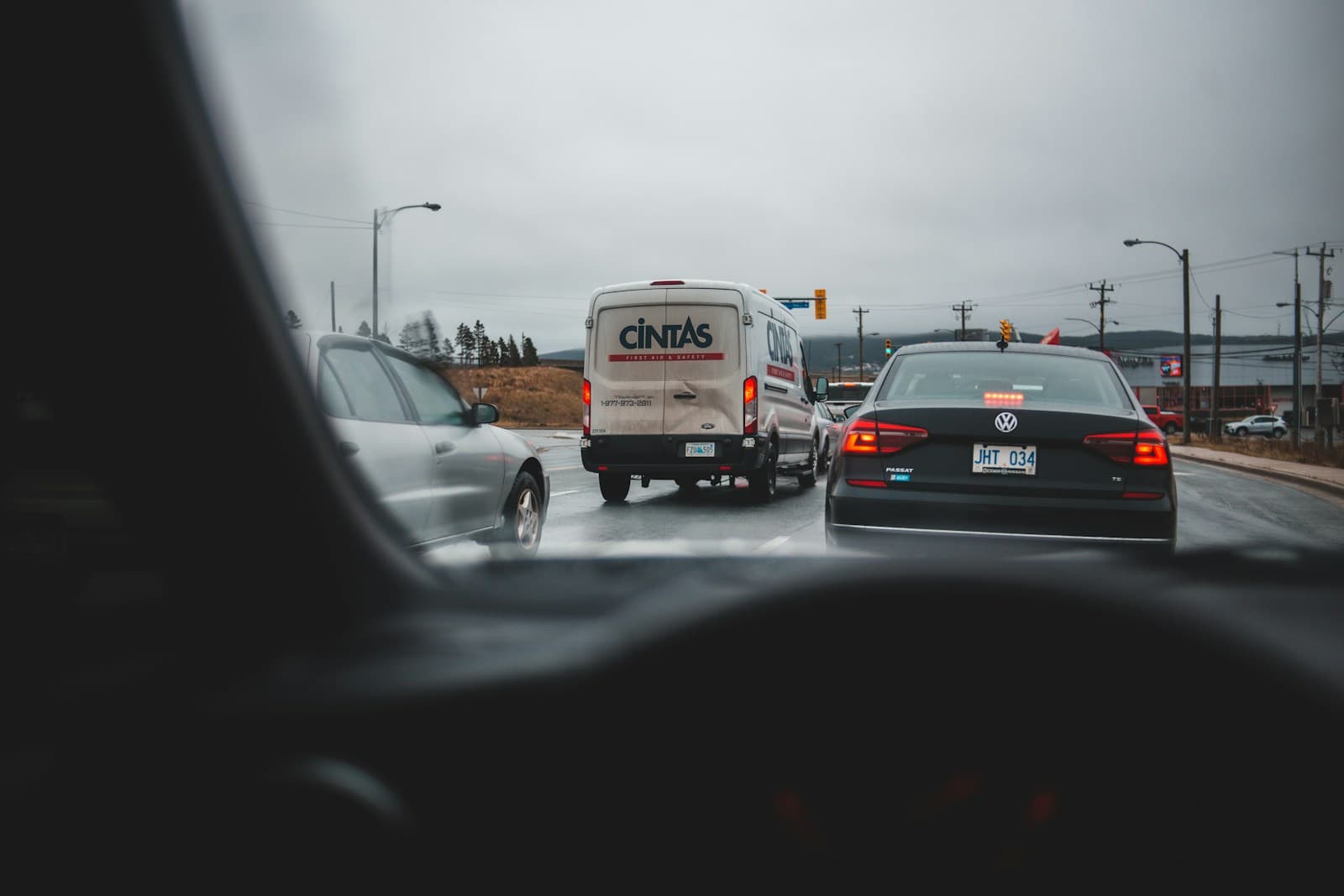 View through car windshield of traffic on wet highway with buses and cars under cloudy sky