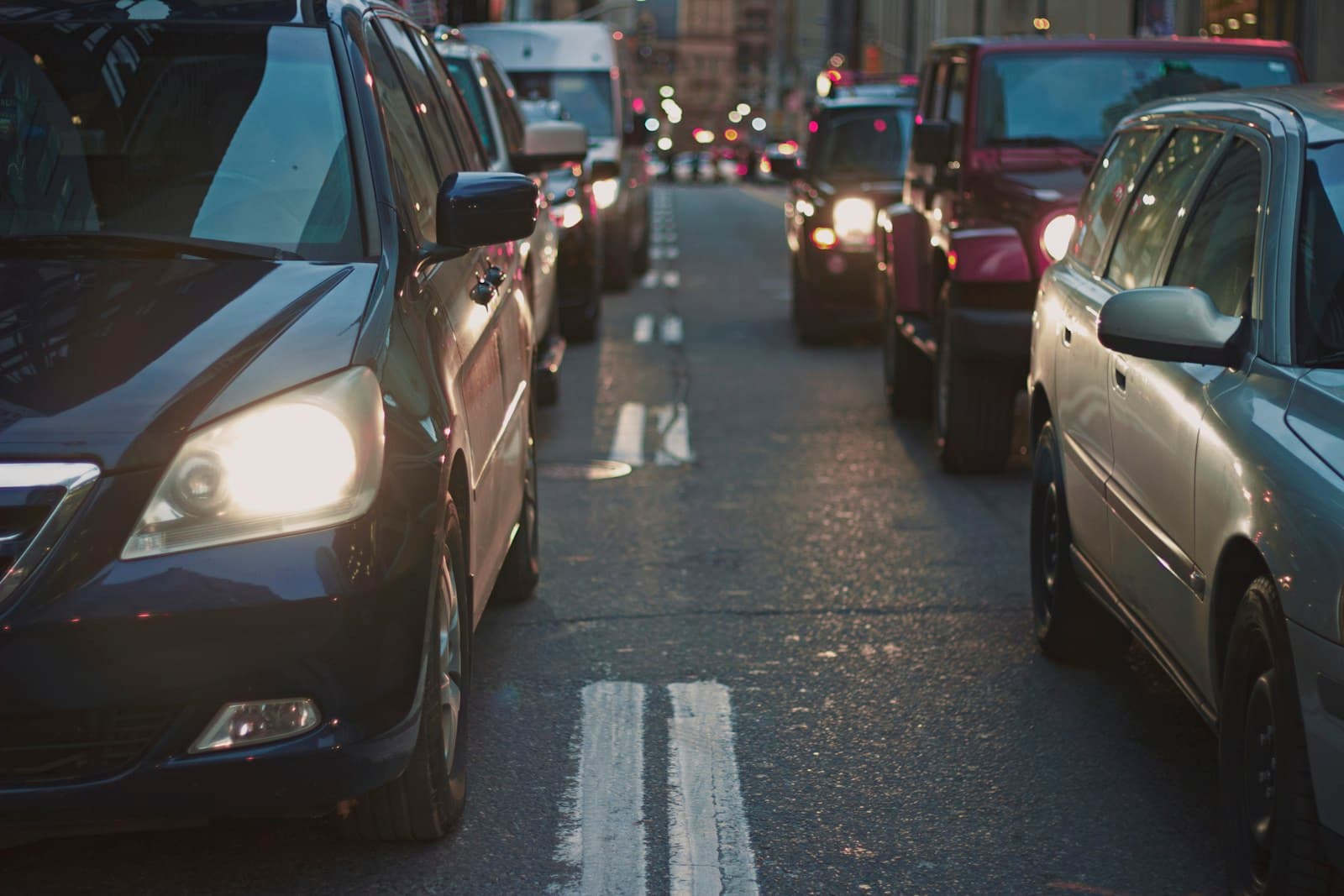 Heavy traffic congestion on city street with cars in multiple lanes and headlights on during low light conditions