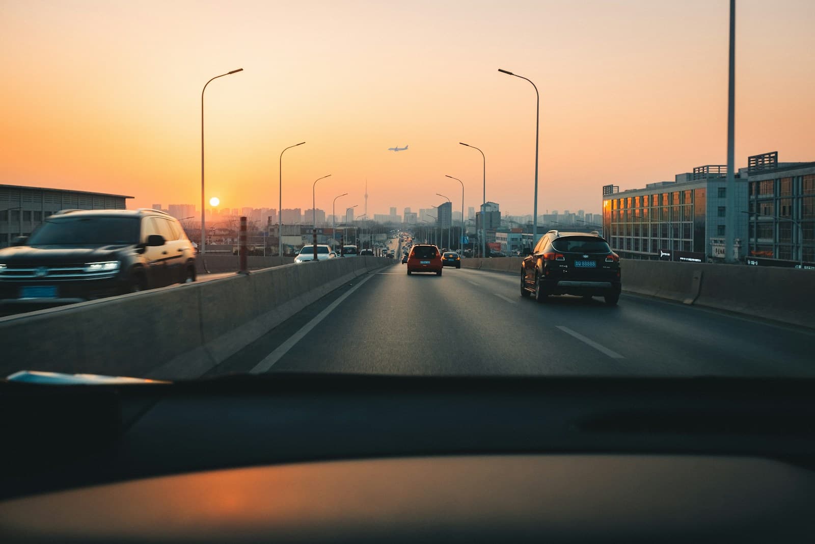 View from inside a car on a multi-lane highway at sunset with city buildings ahead