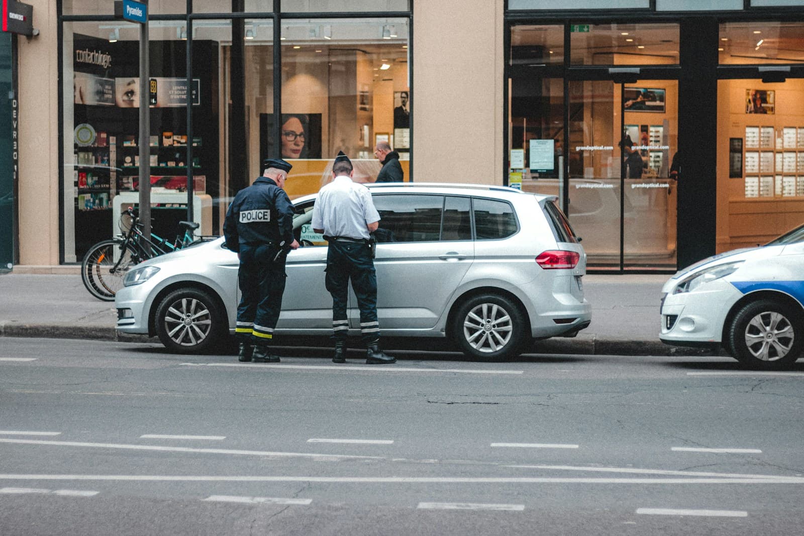 Police officer beside a silver minivan during a traffic stop on a city street