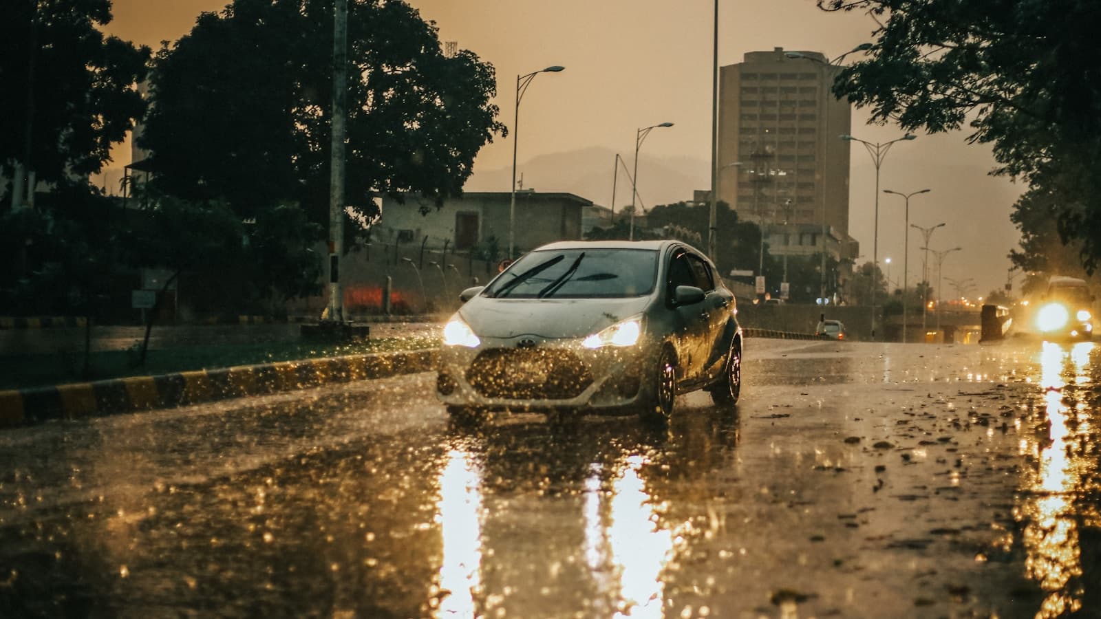 White car driving through a flooded city street during heavy rainfall