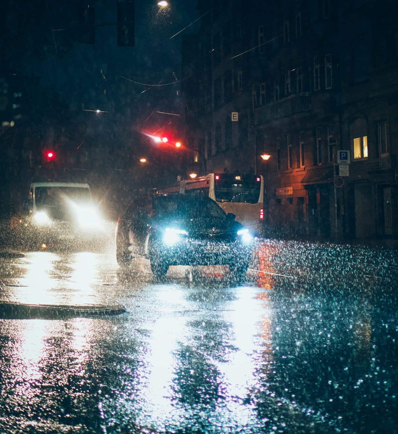 Vehicles driving through flooded city streets at night in heavy rain
