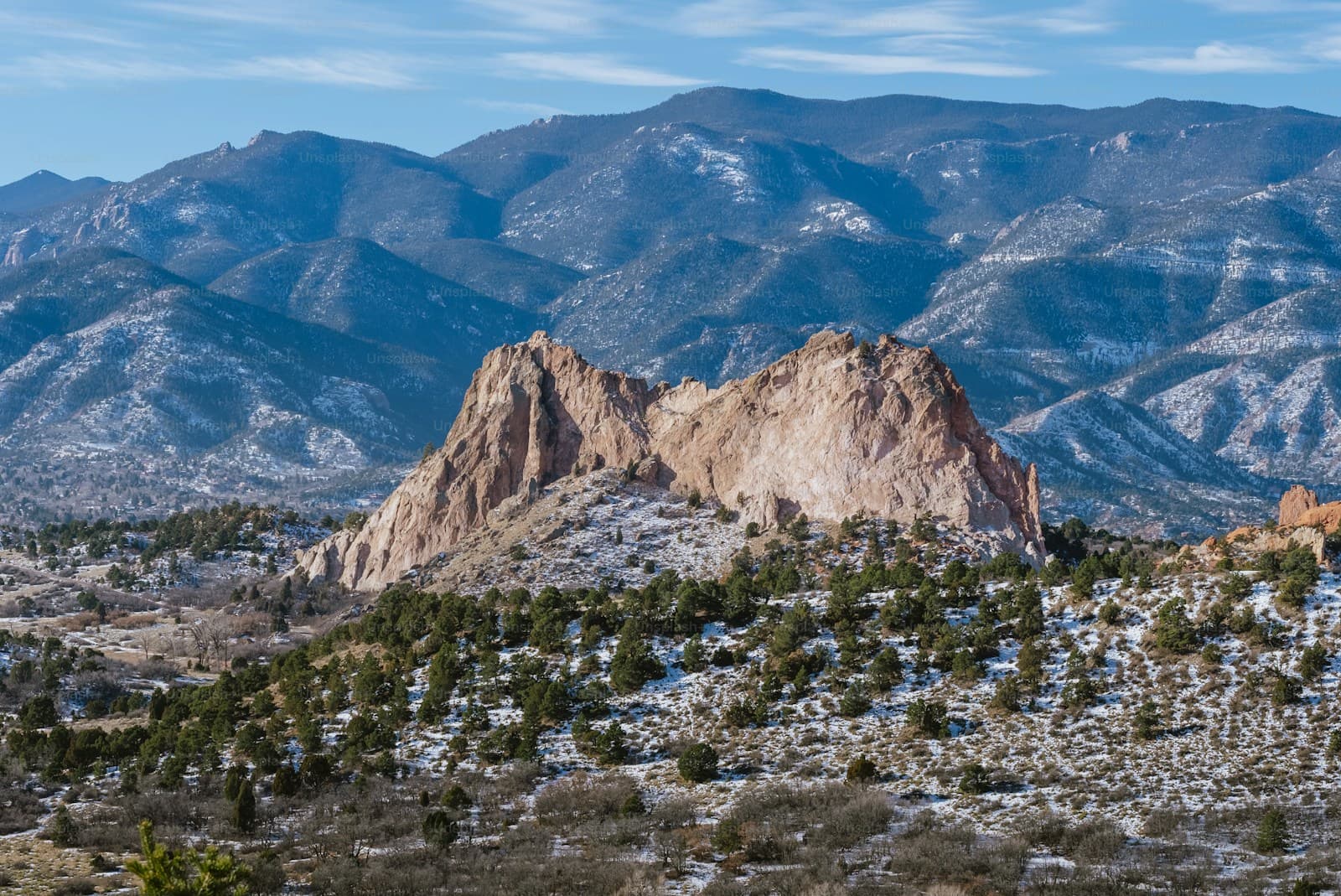 Desert landscape with red rock formations and snow-covered mountains in background