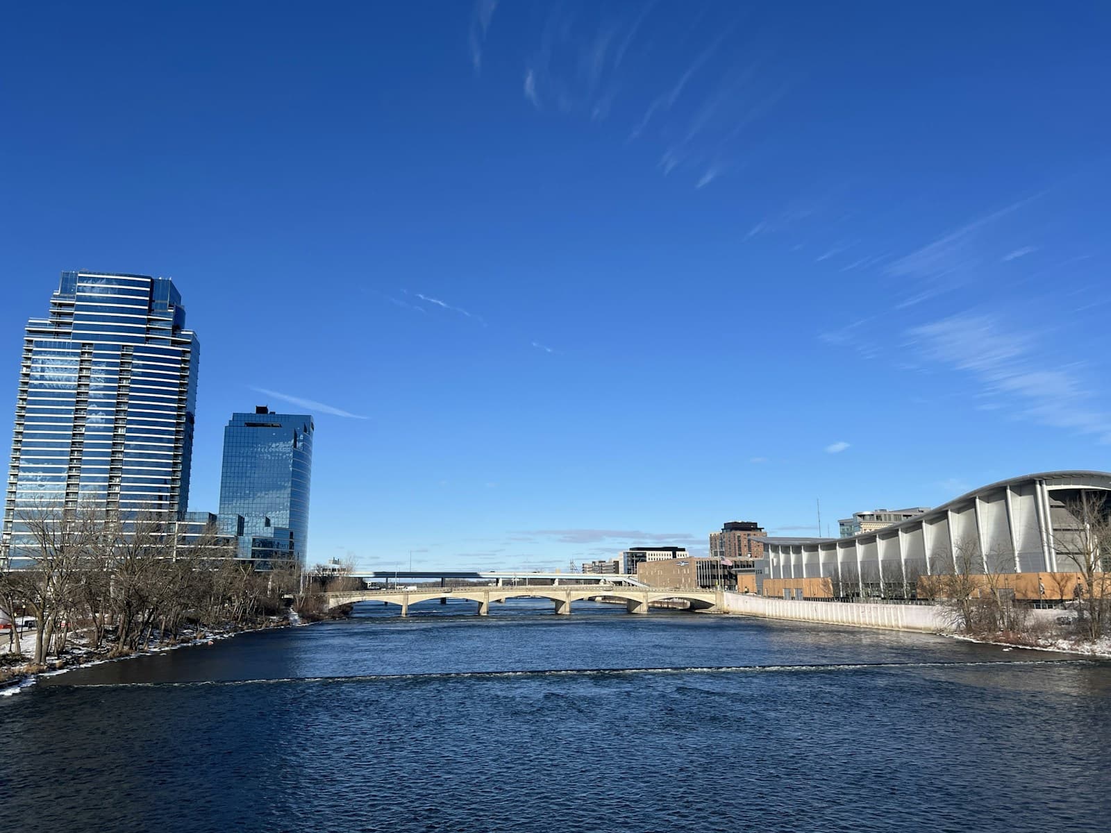 Urban river view with modern skyscrapers and office buildings along the waterfront under blue sky