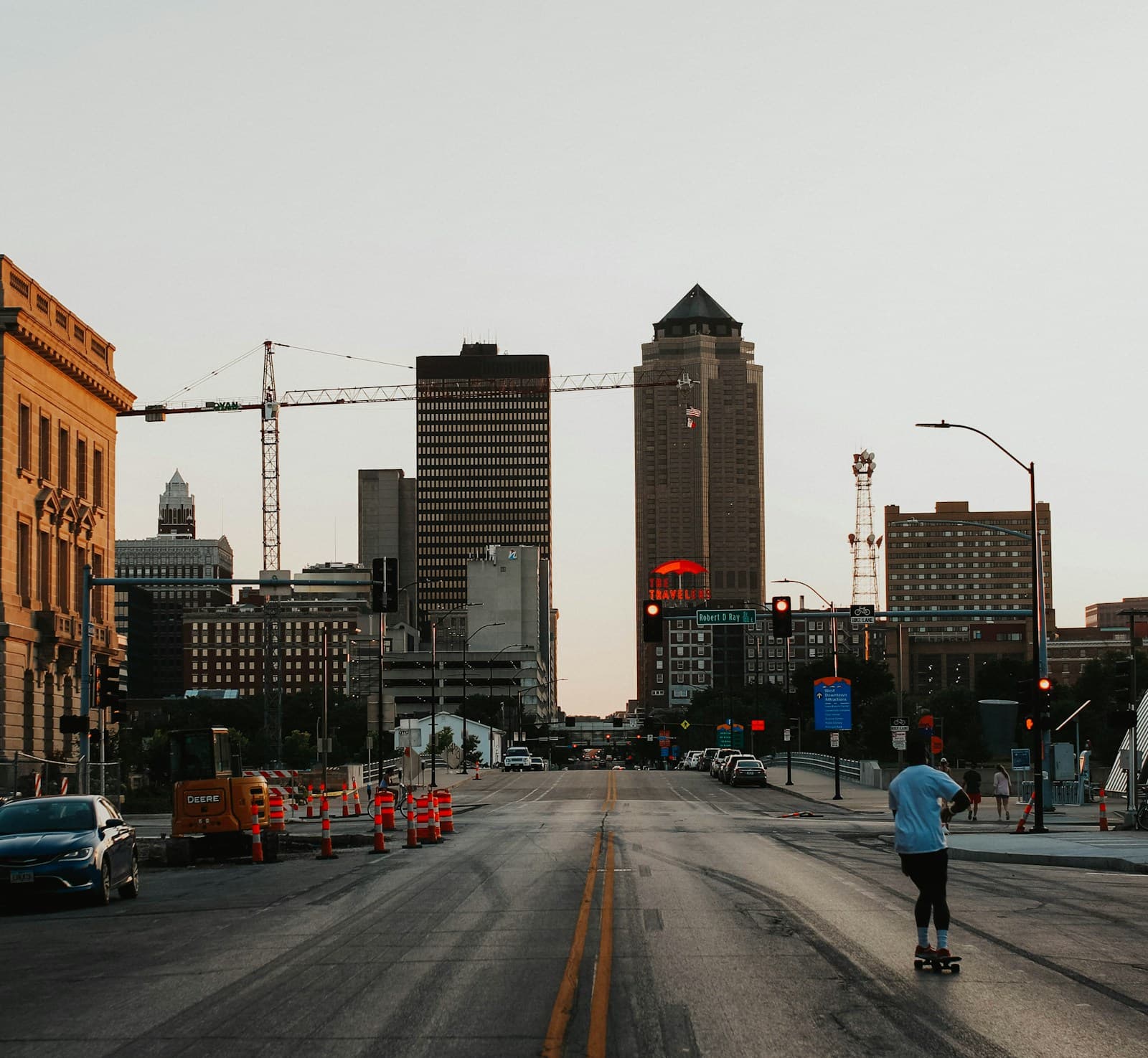 Downtown city street view with skyscrapers, construction barriers, and people during golden hour lighting
