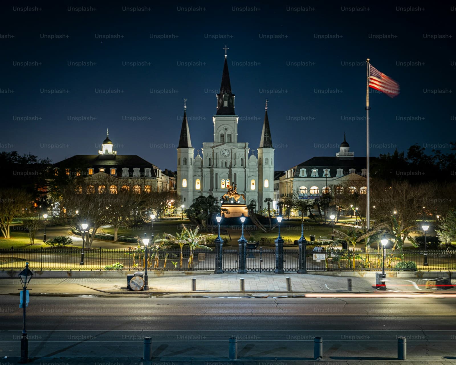 St. Louis Cathedral in Jackson Square, New Orleans at night with American flag and historic buildings illuminated