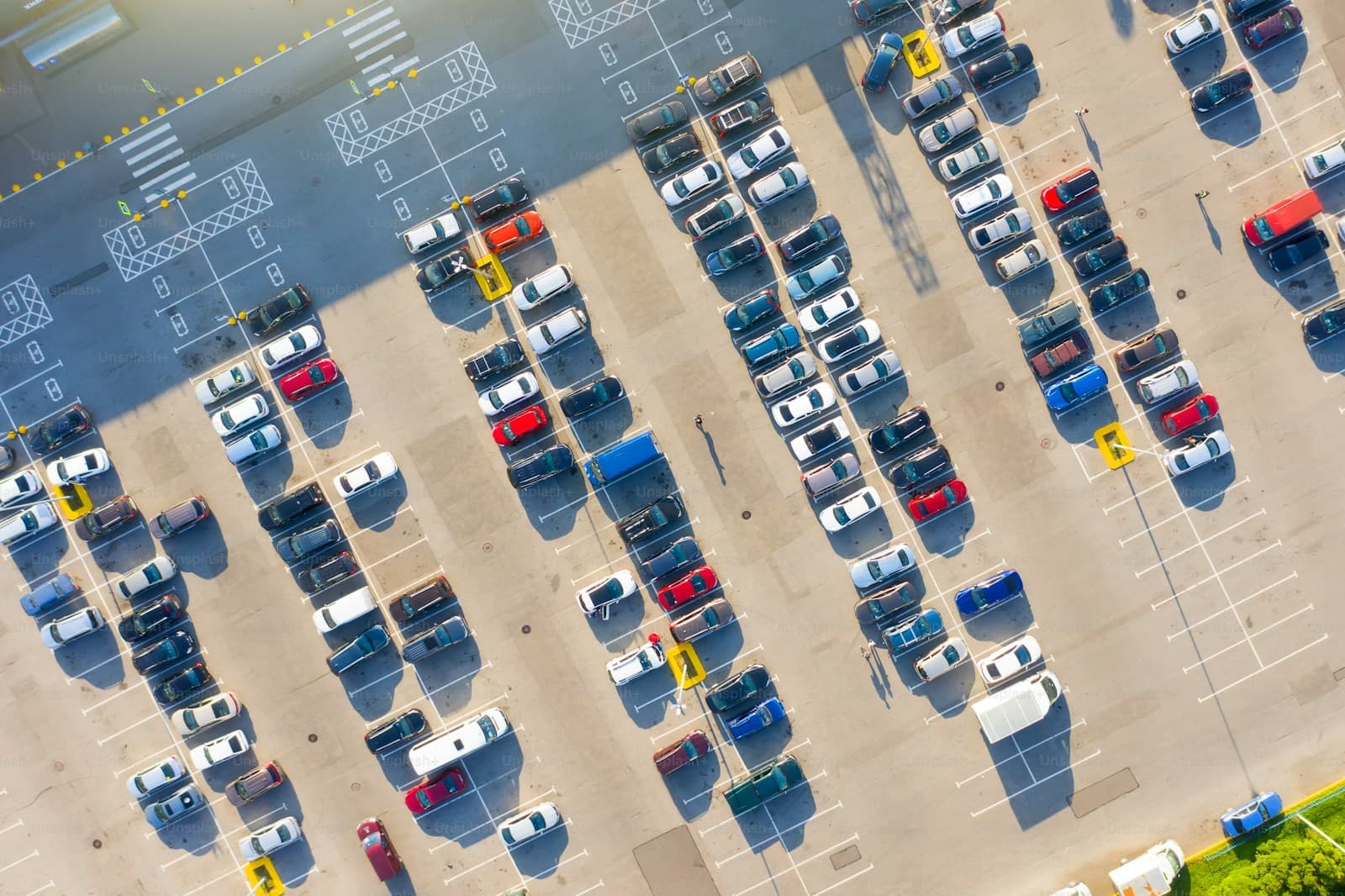 Aerial view of crowded parking lot with cars arranged in organized rows and marked parking spaces