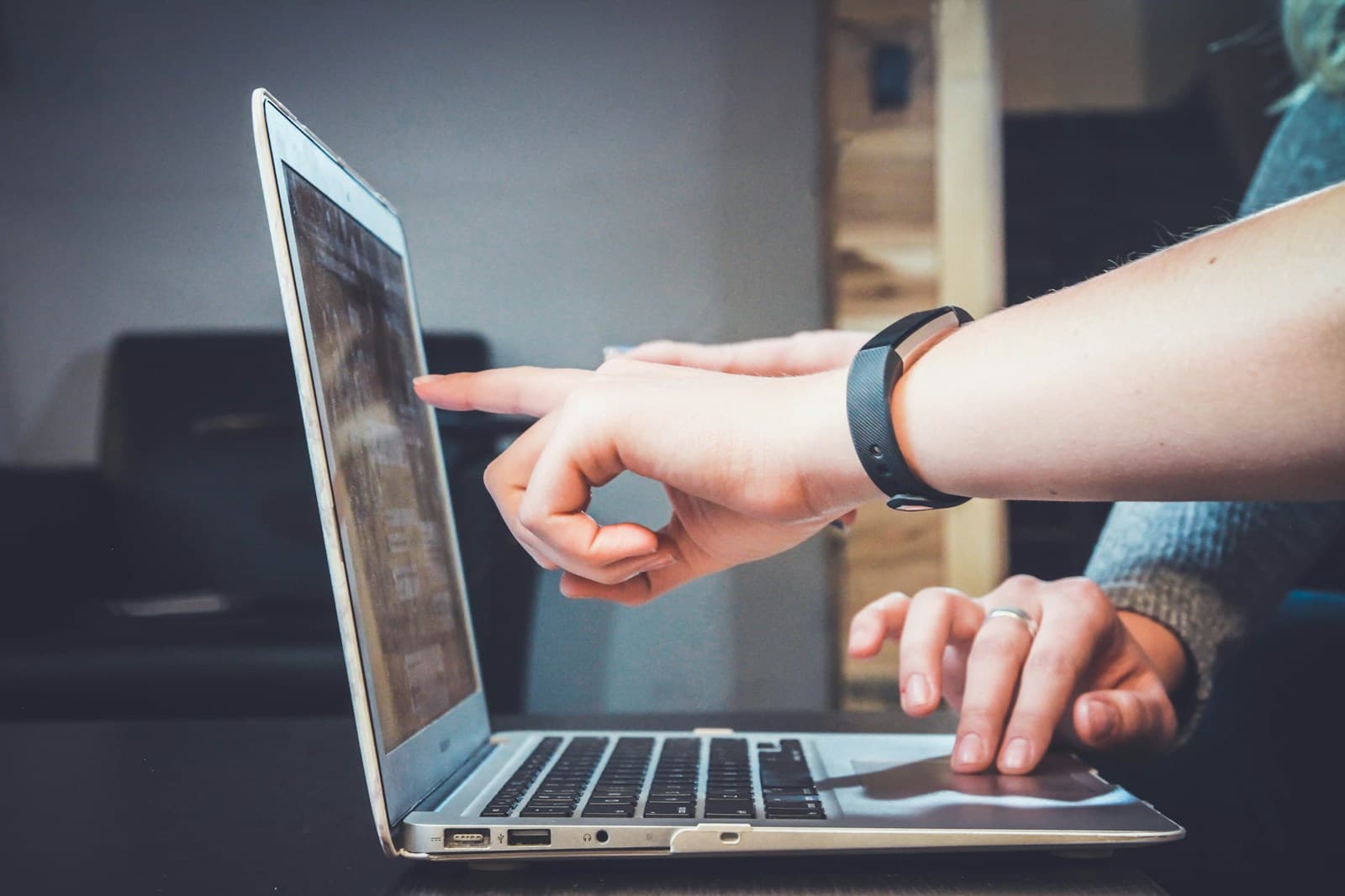 Person pointing at a silver laptop screen while explaining something