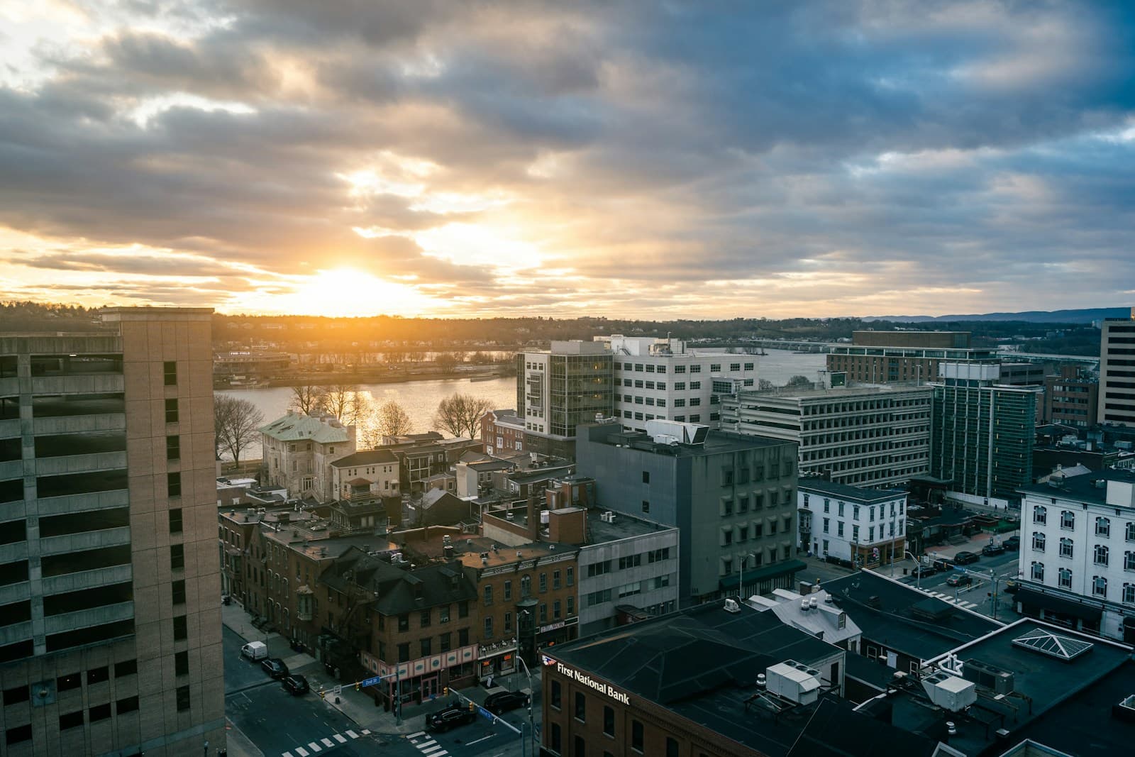 Aerial view of downtown city buildings at sunset with dramatic cloudy sky and golden hour lighting
