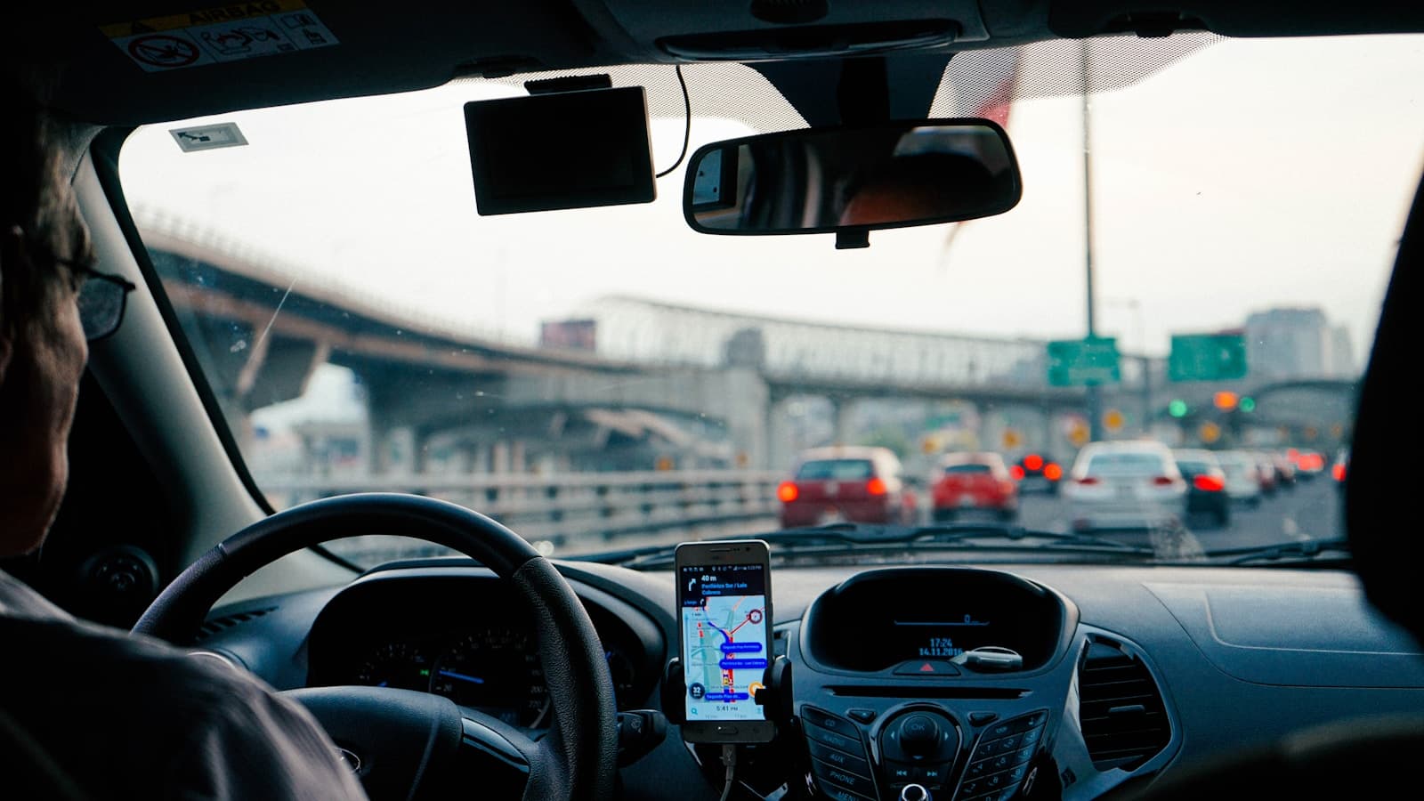 Driver on a busy multi-lane freeway with a navigation app running on a dash-mounted phone