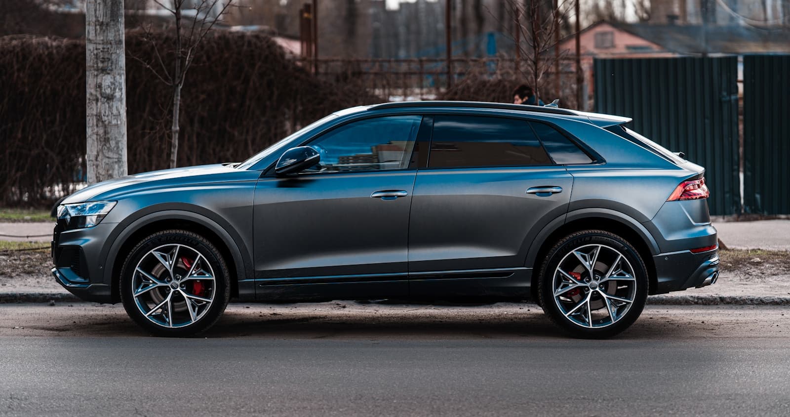 Dark gray luxury SUV parked in an urban setting with bare trees behind it
