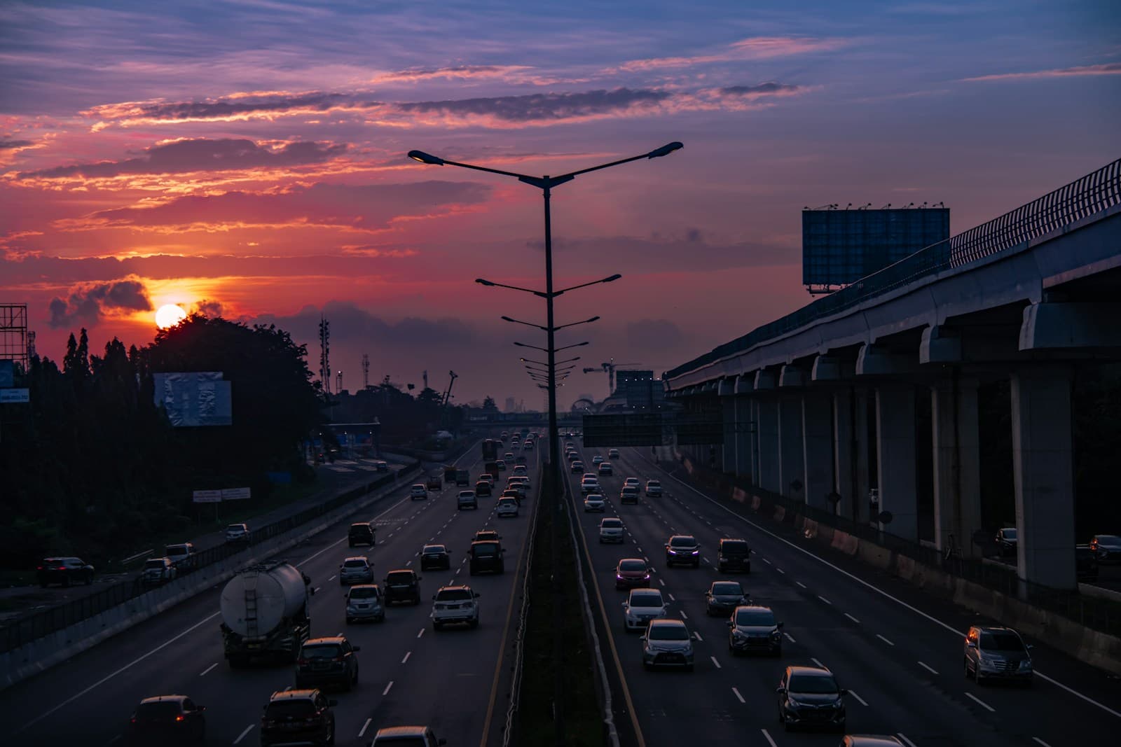 Sunset over busy highway with heavy traffic and colorful orange-pink sky