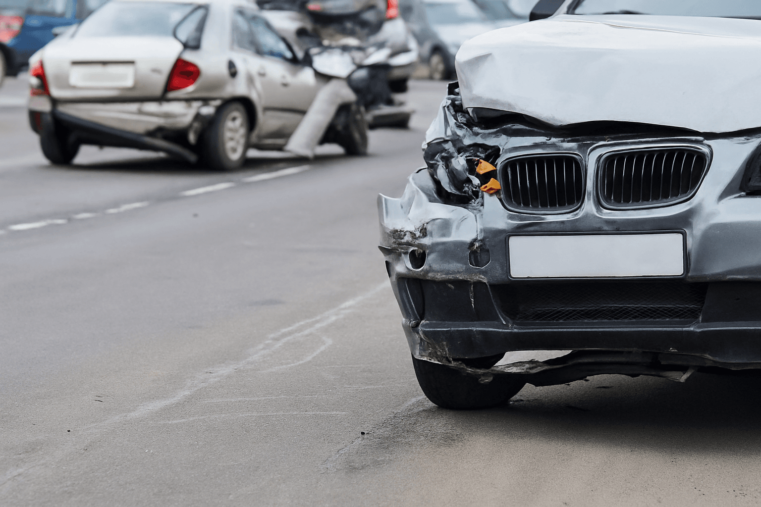 Car accident scene with damaged BMW in foreground and other crashed vehicles on road