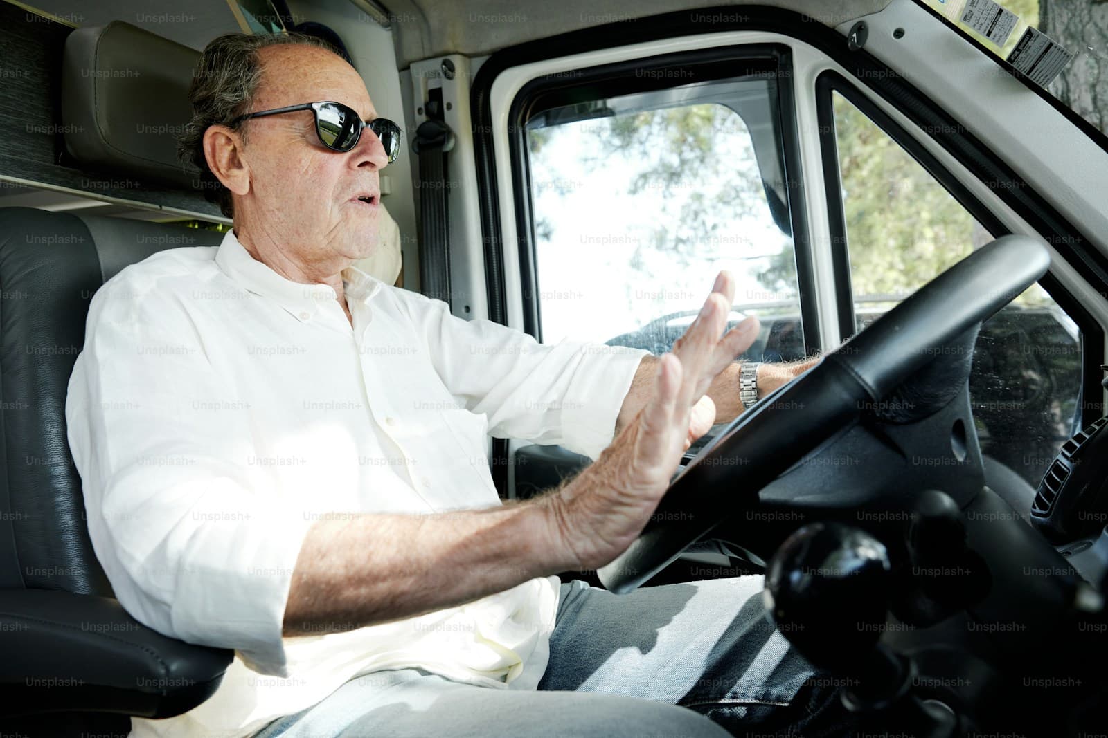 Older man in sunglasses at the wheel of a large truck or motorhome