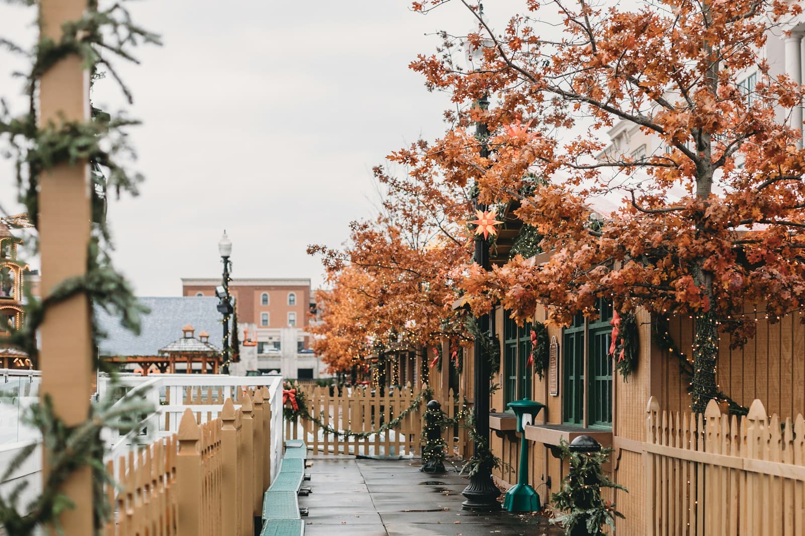 Wooden walkway with autumn trees showing orange fall foliage and traditional buildings in background