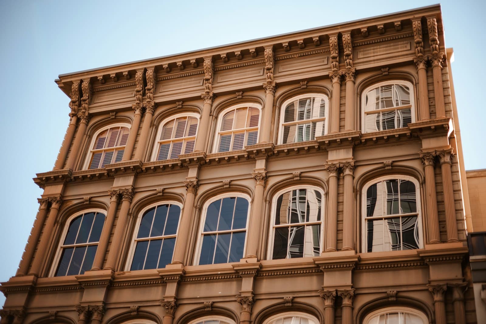 Historic Victorian building facade with ornate arched windows and decorative architectural details in warm sunlight