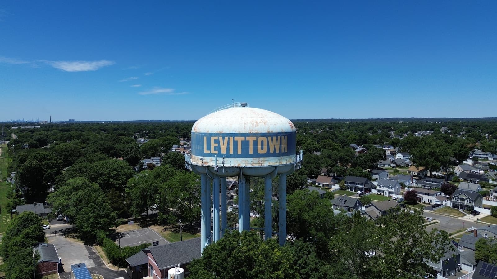 Aerial view of Levittown water tower rising above suburban neighborhood with homes and trees