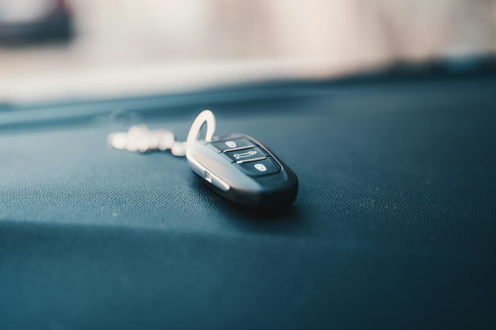 Car key fob with buttons sitting on dark car dashboard