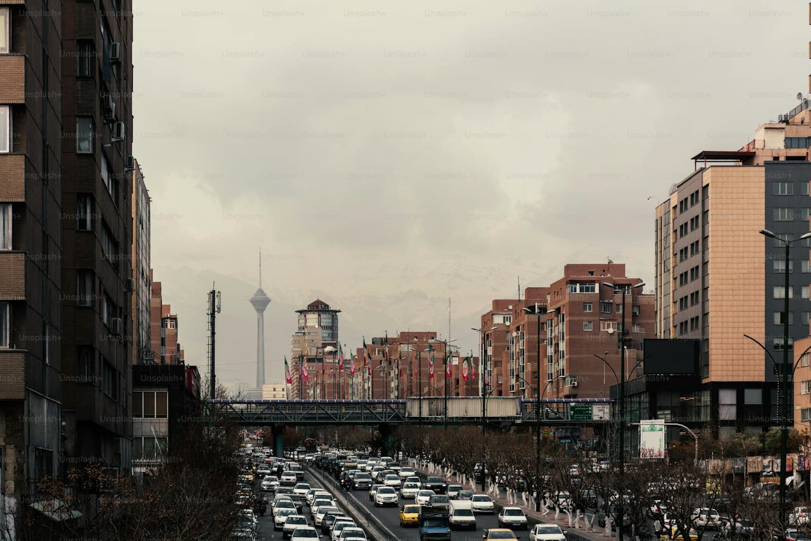 Heavy traffic on multi-lane highway with apartment buildings and telecommunications tower in background