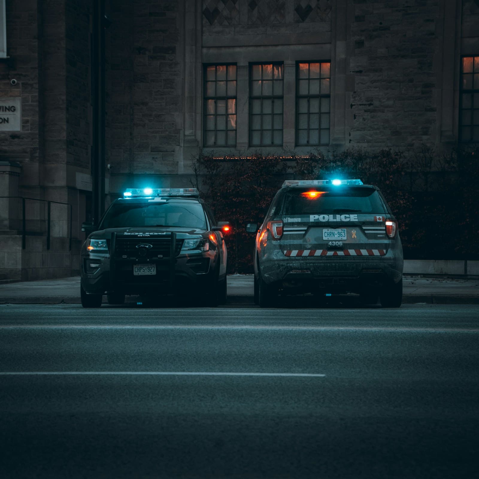 Two police cars with flashing emergency lights parked on a dark city street at night