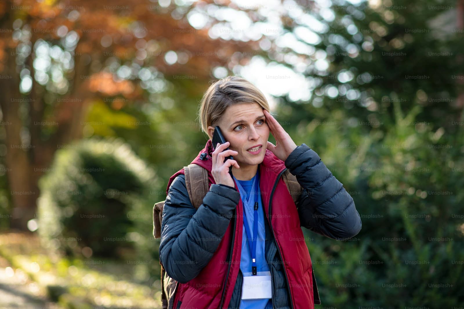 Woman on her phone outdoors in autumn holding her head in frustration