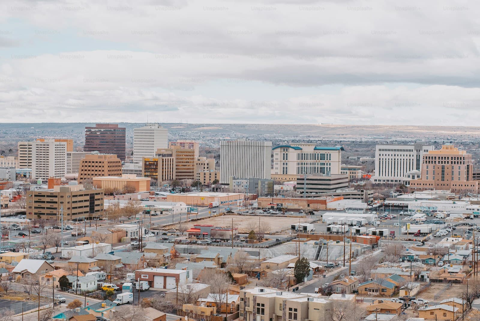 Aerial view of downtown city skyline with high-rise buildings and surrounding residential neighborhoods under cloudy sky