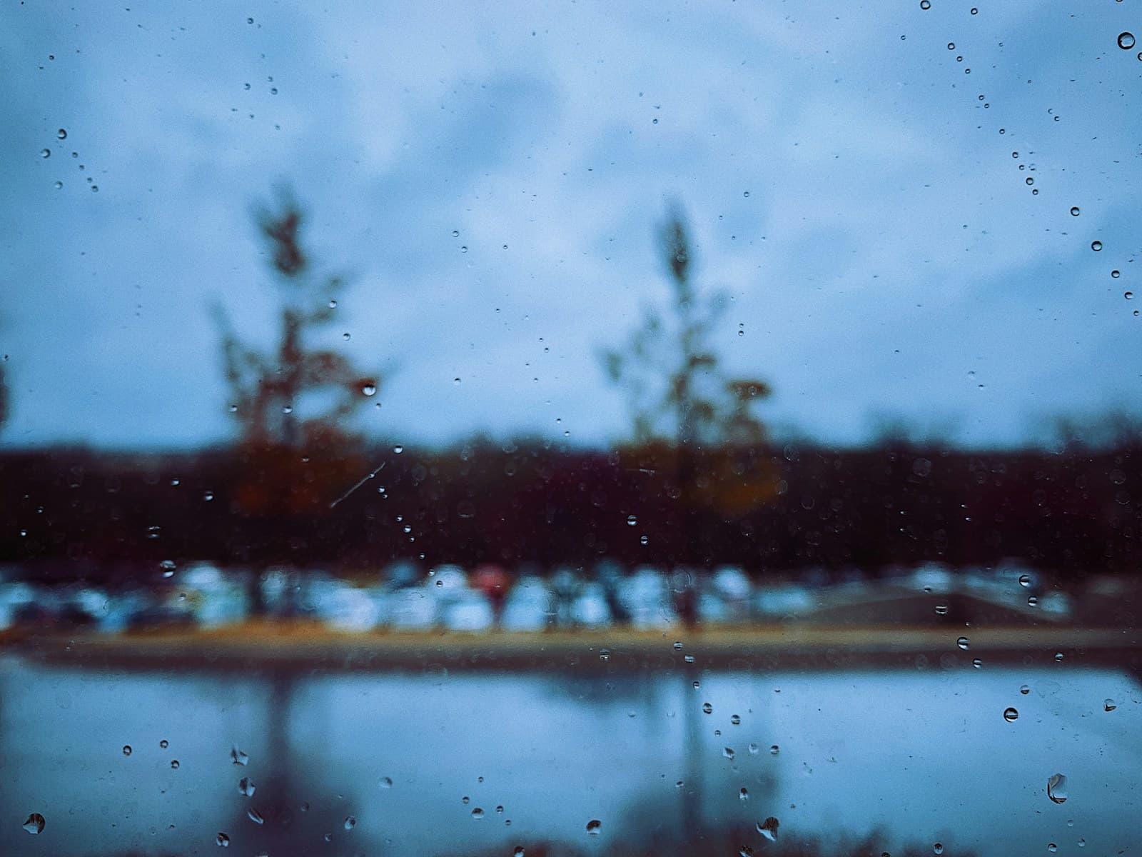 Raindrops on glass with blurred ships in background creating moody atmospheric maritime scene