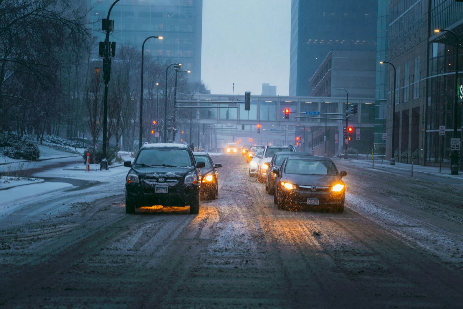 Cars with headlights on moving along a snow-covered city street during a snowstorm