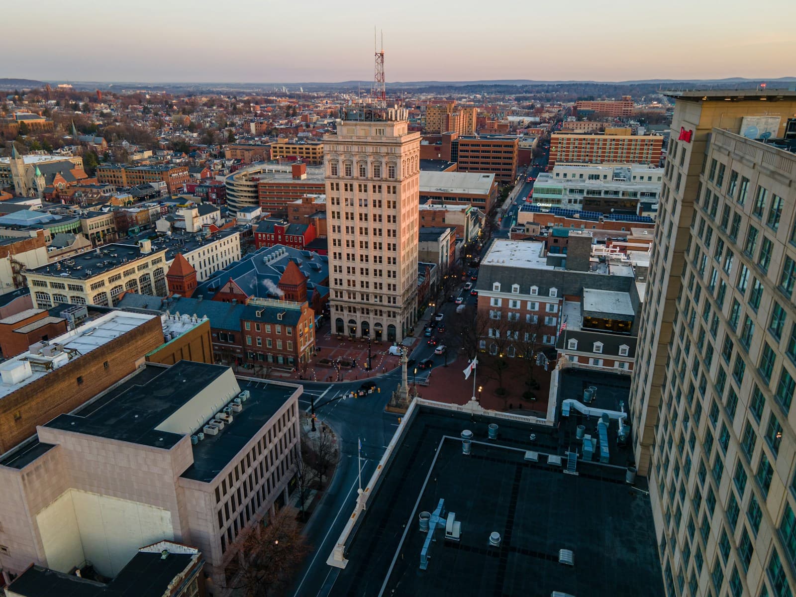 Aerial view of downtown city at sunset with historic and modern buildings in warm golden light