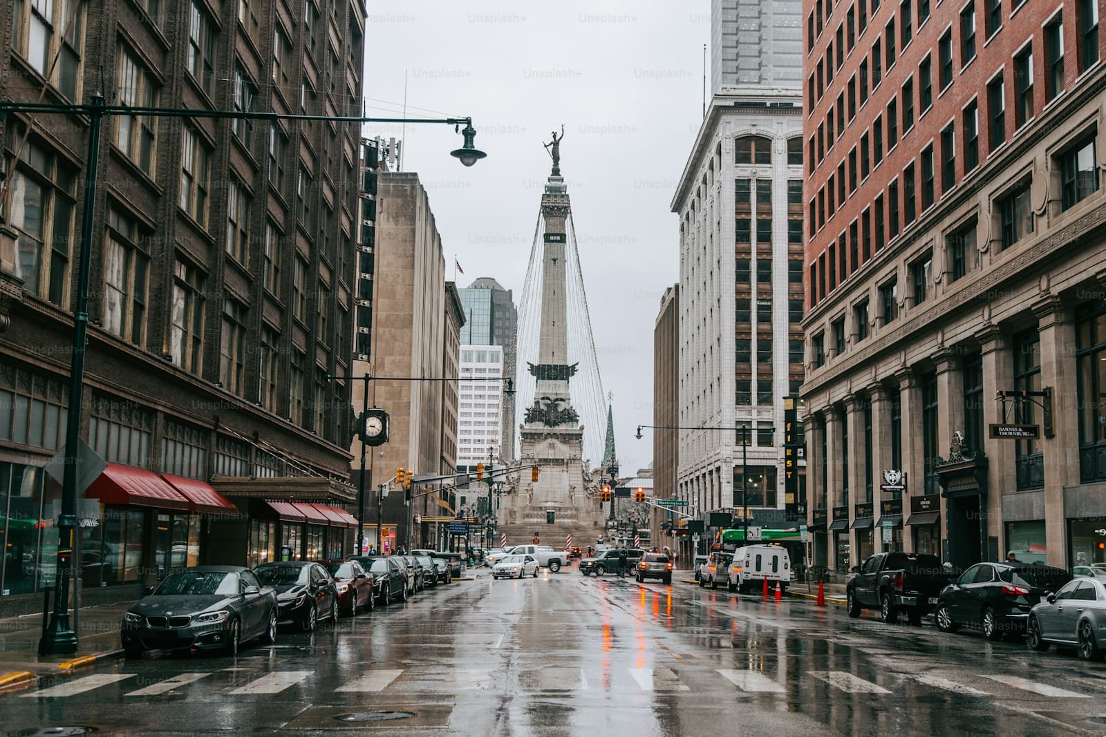 Rainy city street with historic buildings leading to a monument in the distance