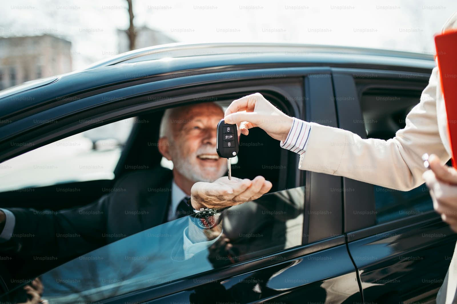 Businessman in car receiving keys from someone outside the vehicle in a professional handover scene