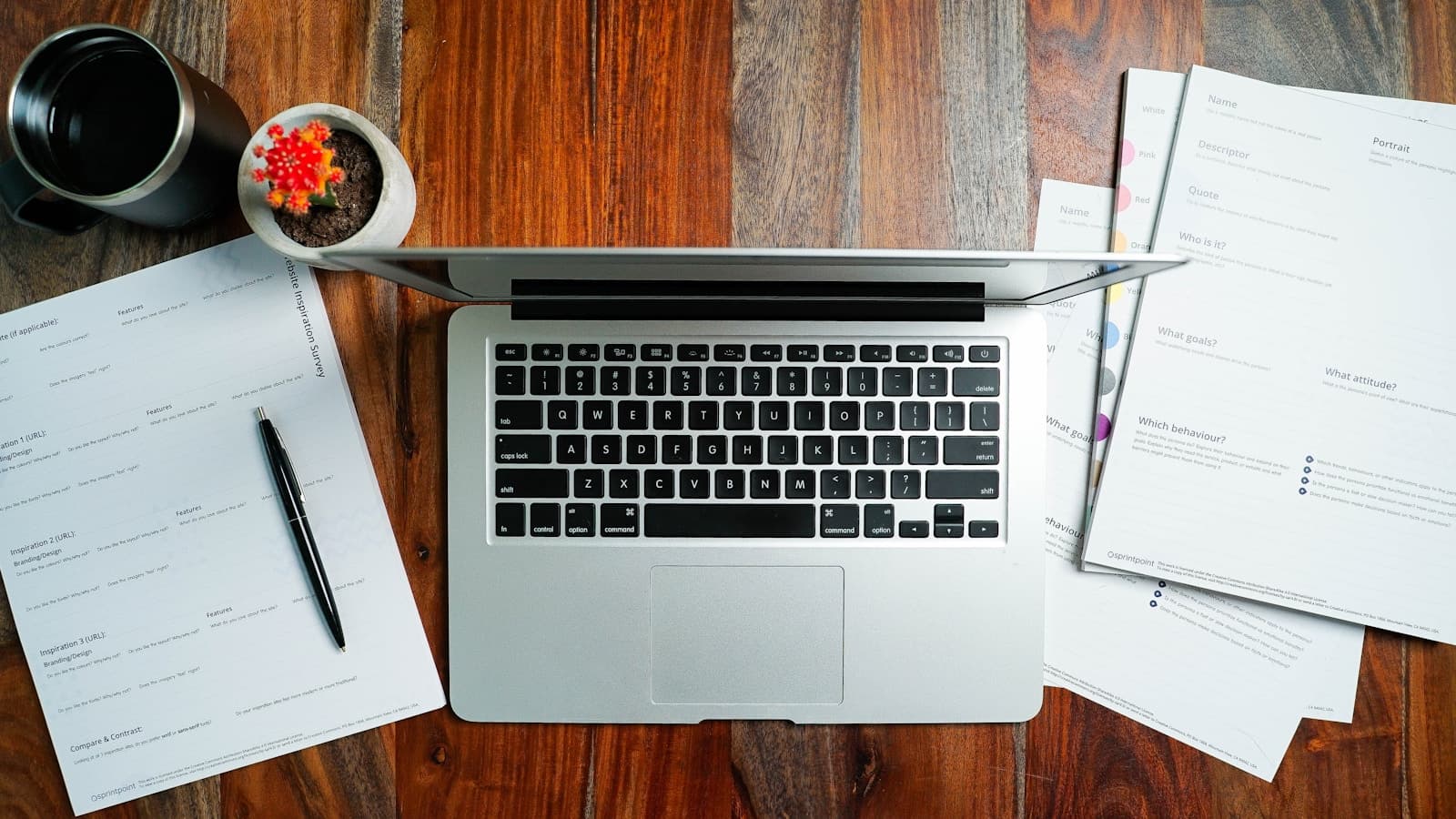 Laptop computer on wooden desk with papers, coffee mug, and snack bowl - overhead workspace view