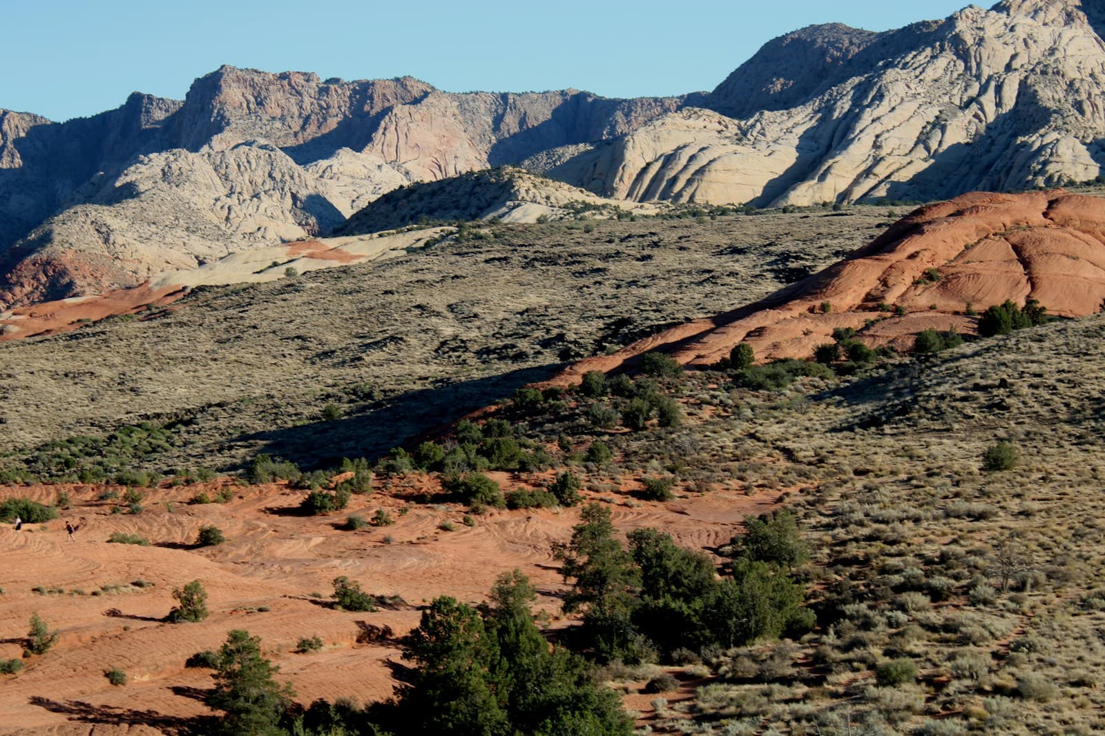Desert landscape with red sandstone formations and layered cliffs under blue sky