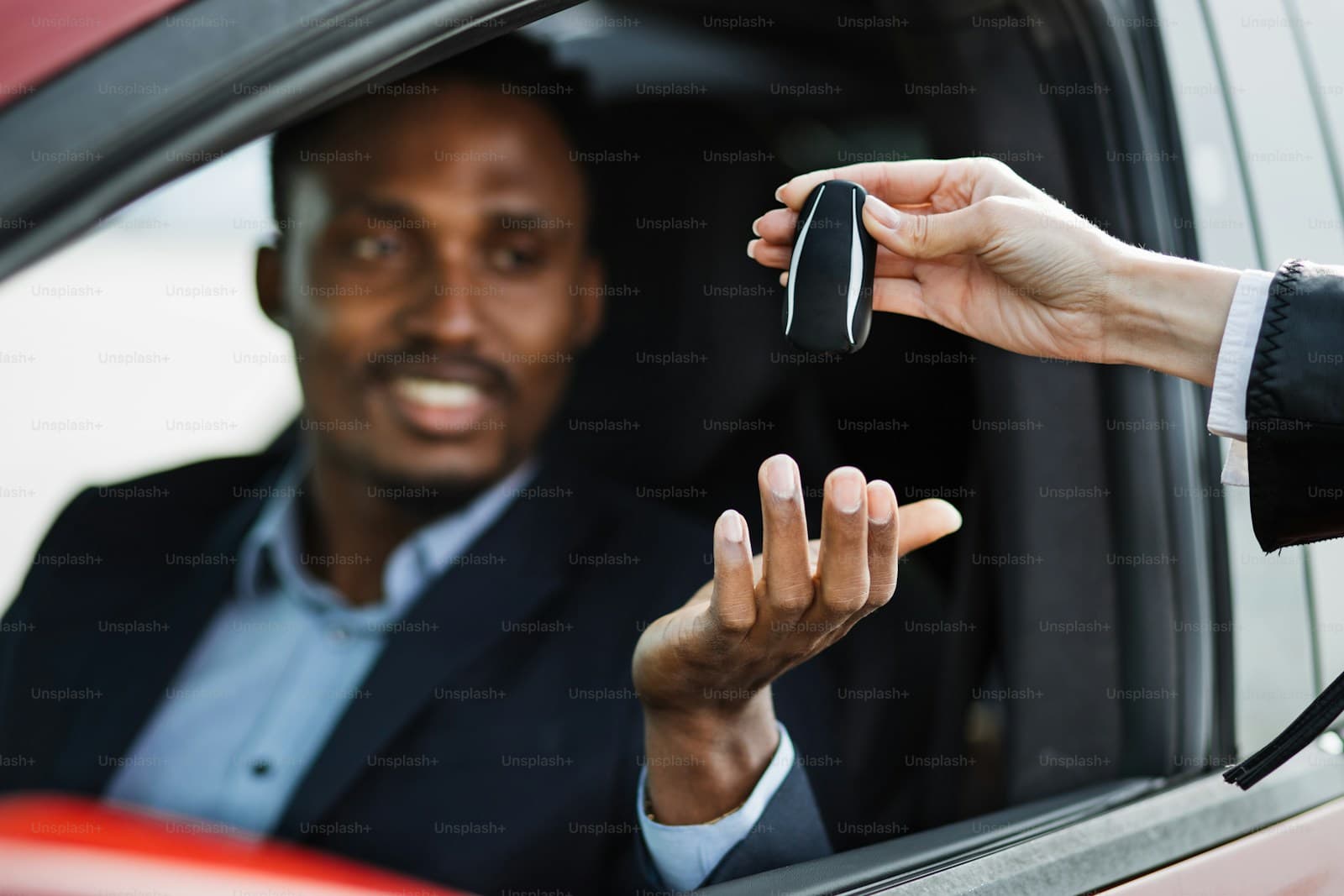 Smiling businessman in car receiving keys from hand outside vehicle window