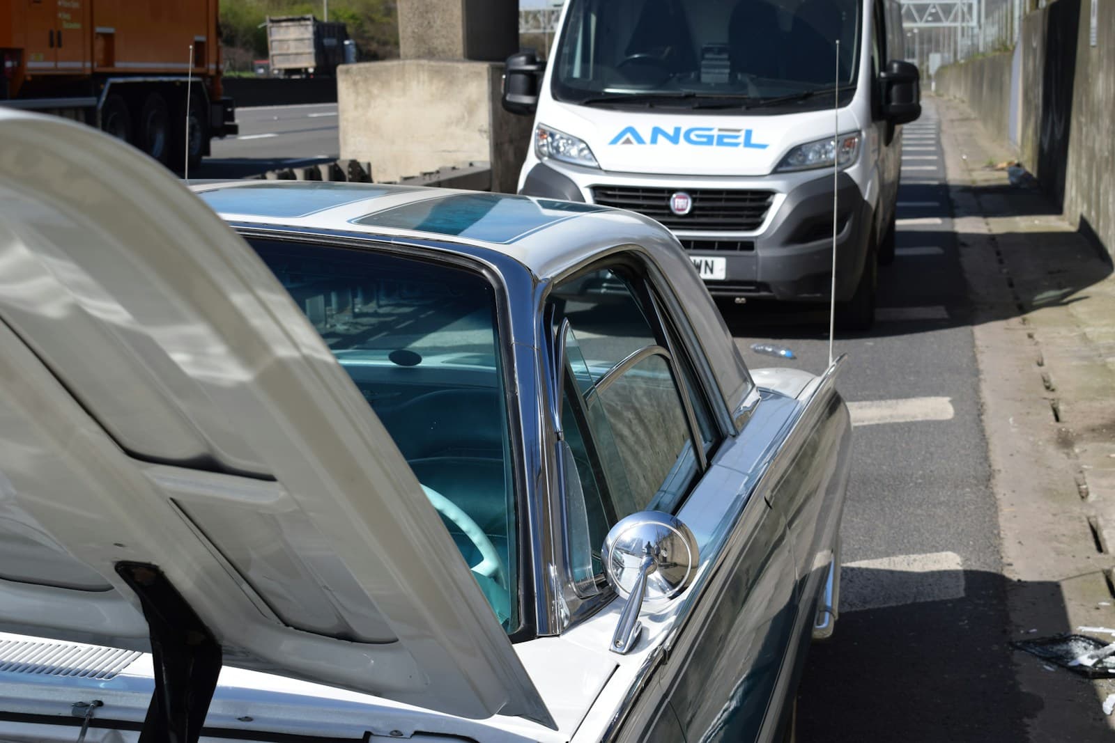 Vehicles parked in a service area, a dark car with its door open in the foreground