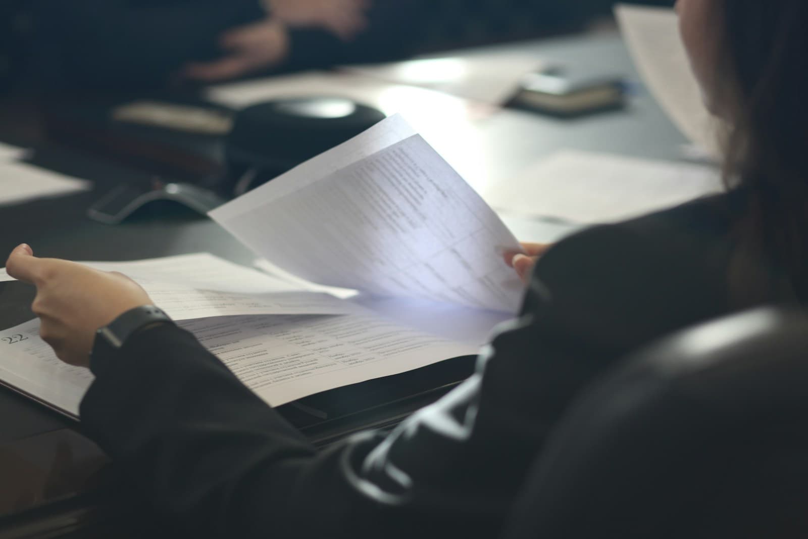 Person reviewing documents and papers at office desk in professional work setting