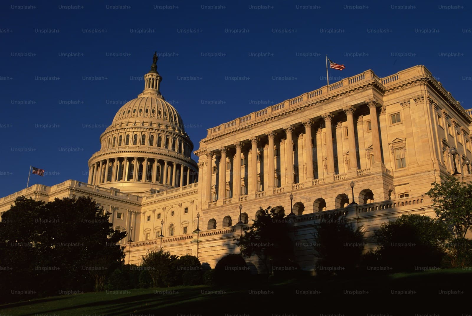 US Capitol building at sunset with golden lighting on white stone facade and dome against blue sky
