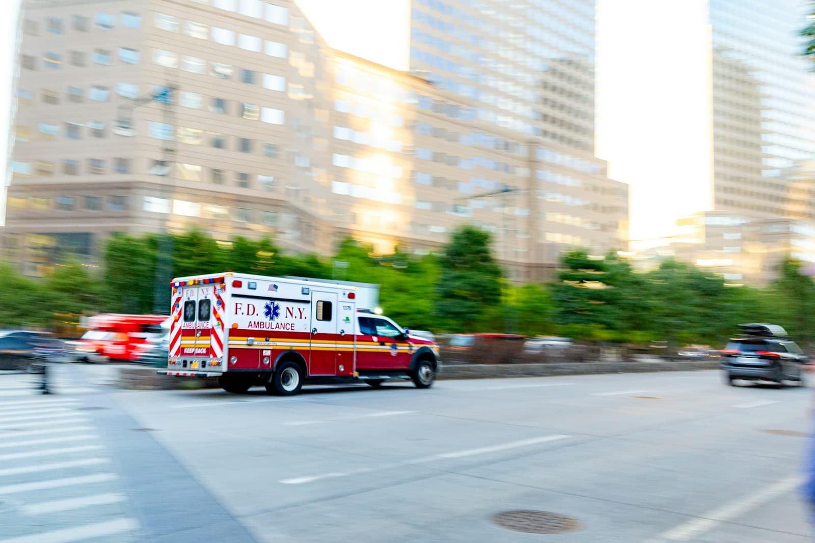 Emergency ambulance speeding through city street with motion blur effect, tall buildings in background