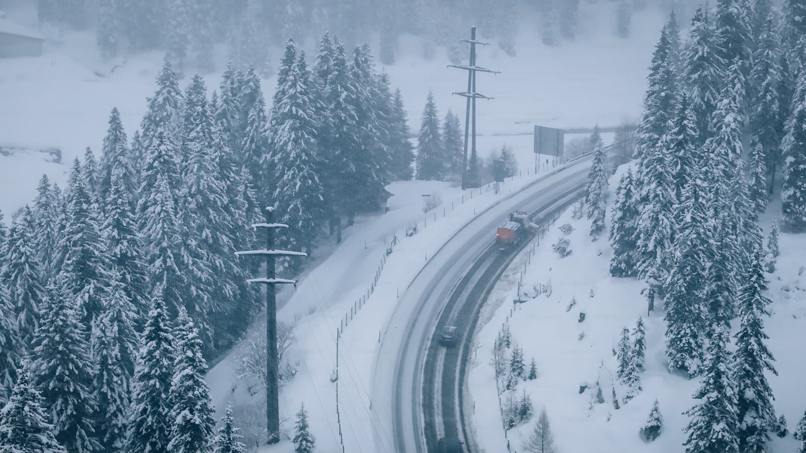 Curved highway winding through snow-covered evergreens in a mountain winter landscape
