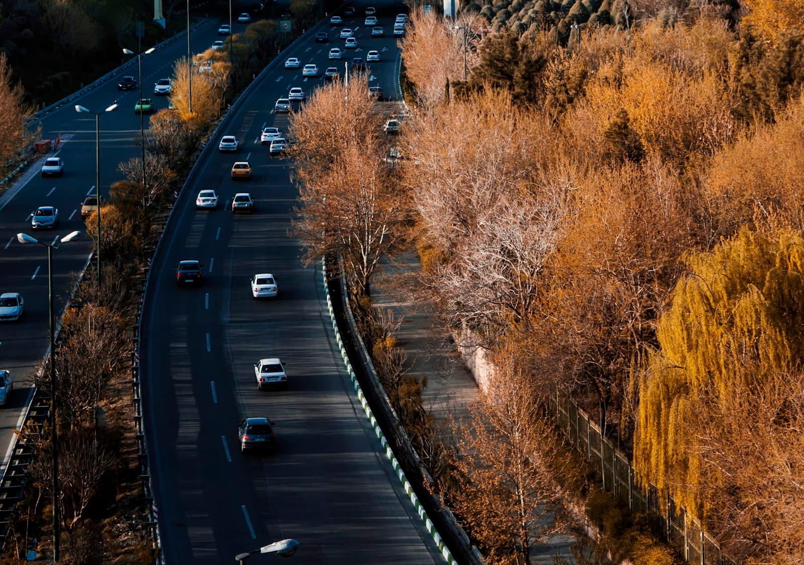 Aerial view of a busy multi-lane highway framed by golden autumn trees