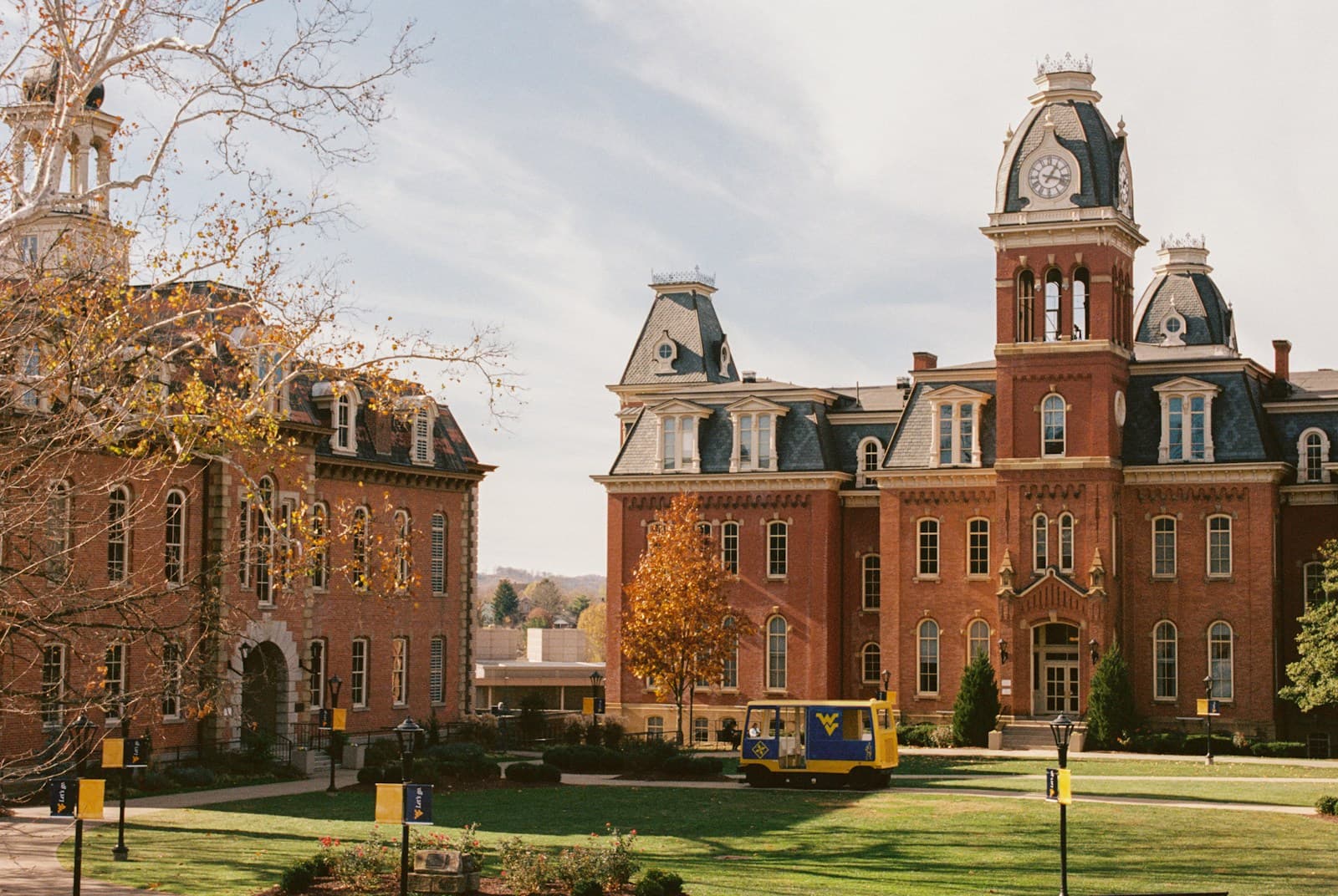 Victorian brick university buildings with mansard roofs and towers surrounded by autumn trees on campus