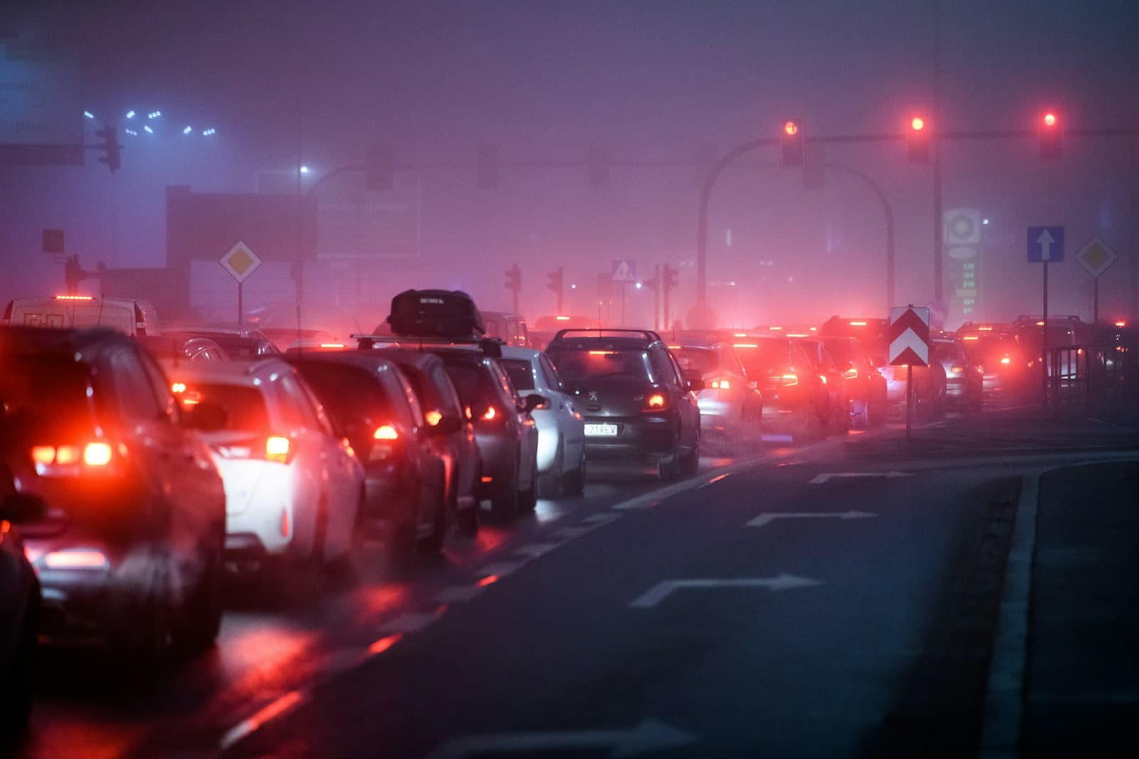 Heavy nighttime traffic jam with red brake lights glowing in foggy purple atmosphere on city street