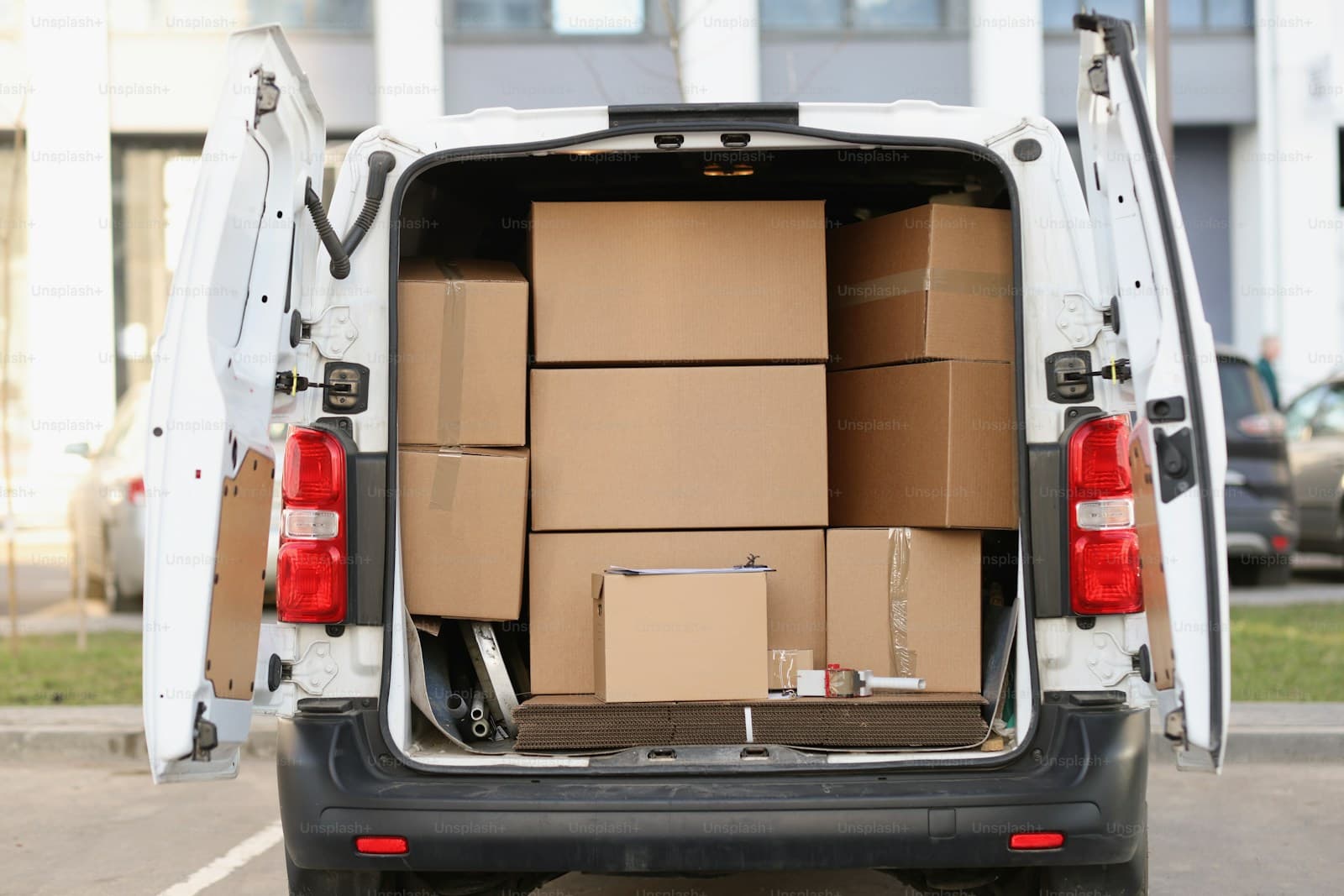 White delivery van with rear doors open revealing cargo packed with boxes