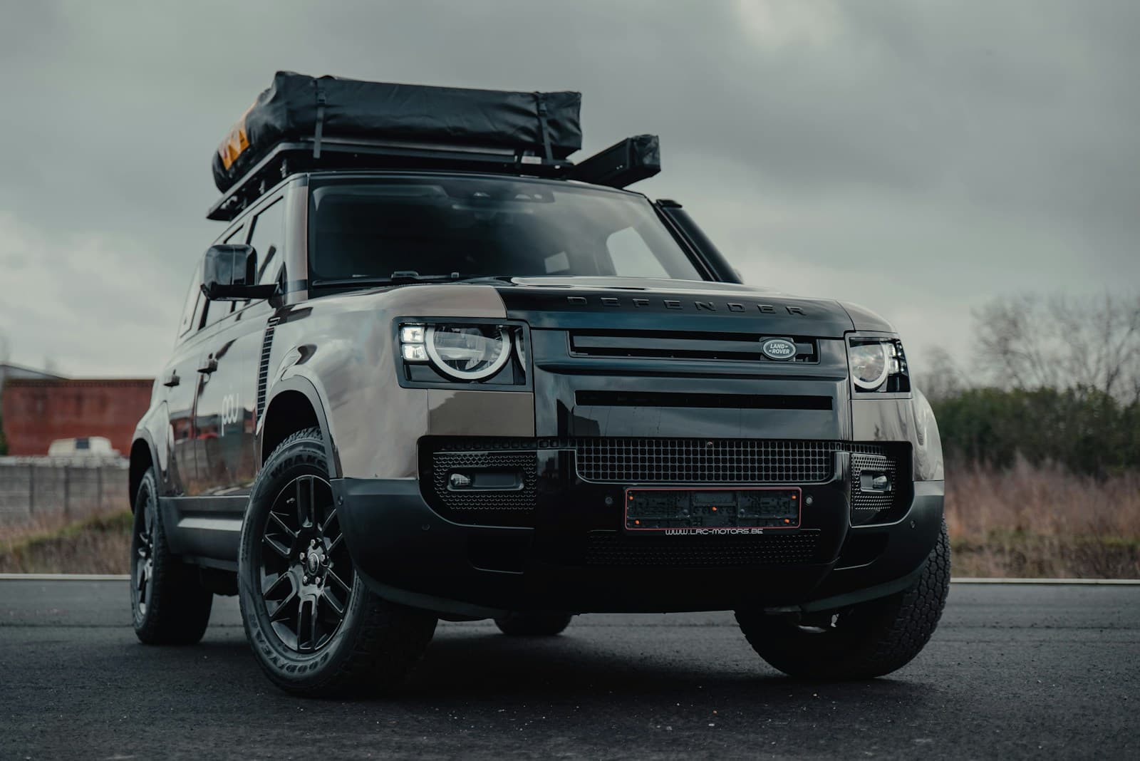 Rugged light-colored SUV with roof cargo racks parked on wet pavement