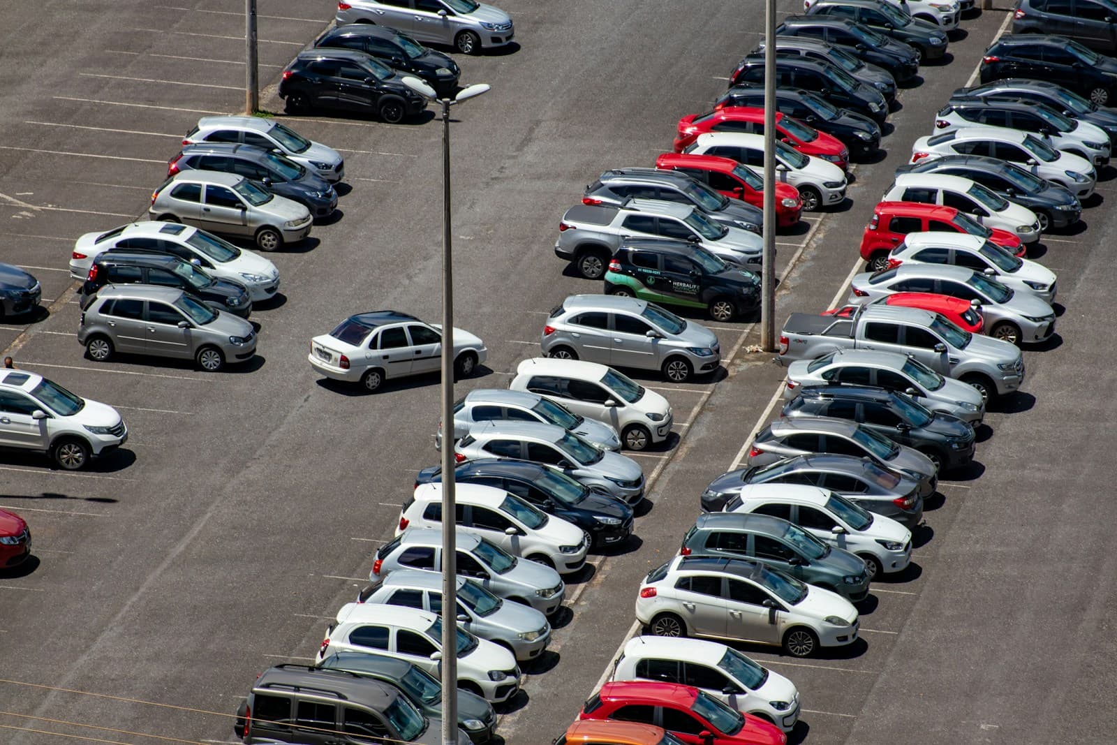 Aerial view of crowded parking lot with many cars parked in organized rows